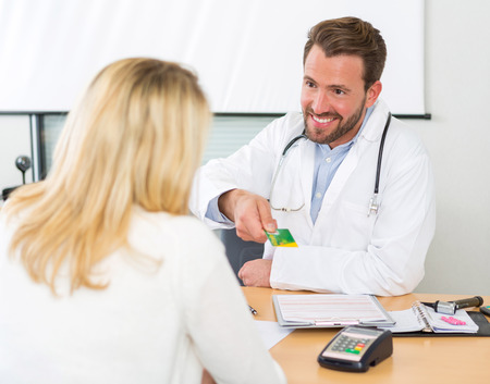 Viewof a Young attractive doctor taking health insurance cardの写真素材