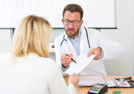 View of a Young attractive doctor giving prescription to a patientの写真素材