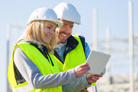 View of Two workers working outside with a tablet on a construction siteの写真素材