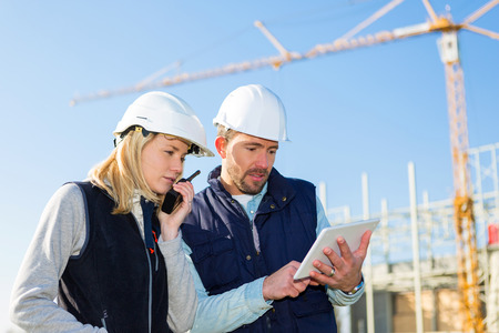 View of Two workers working outside with a tablet on a construction siteの写真素材