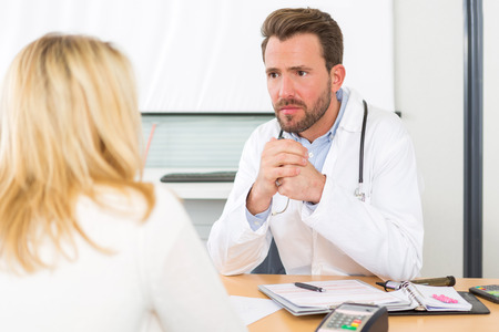 View of a Young attractive doctor listening his patientの写真素材