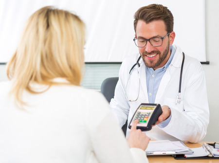 View of a Patient paying the doctor by credit cardの写真素材