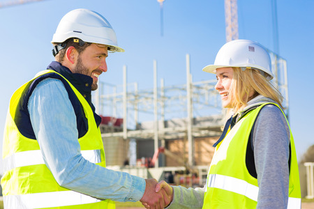 View of a architect and worker handshaking on construction siteの写真素材
