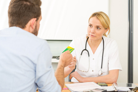 View of a Young attractive woman doctor taking health insurance cardの写真素材