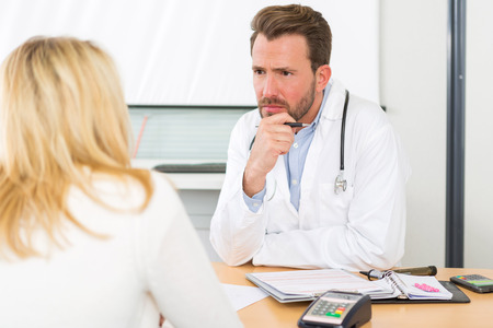 View of a Young attractive doctor listening his patientの写真素材
