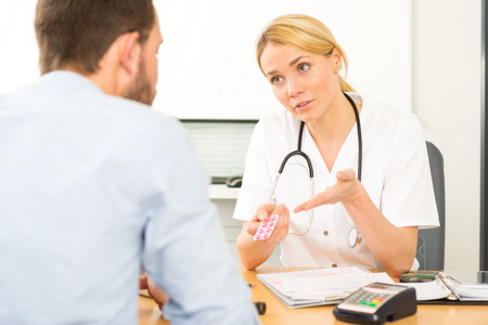 View of a Young attractive woman doctor giving pills to a patientの写真素材