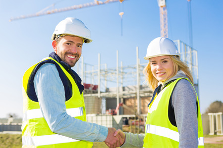 View of a architect and worker handshaking on construction siteの写真素材