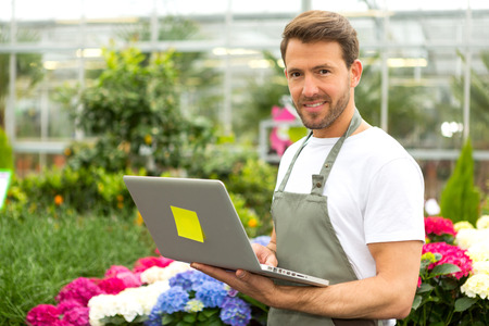 View of a Young attractive man working at the plants nursery using laptopの写真素材