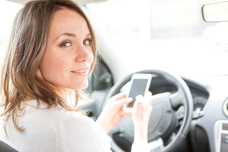 View of a Young attractive woman using mobile phone in his carの写真素材