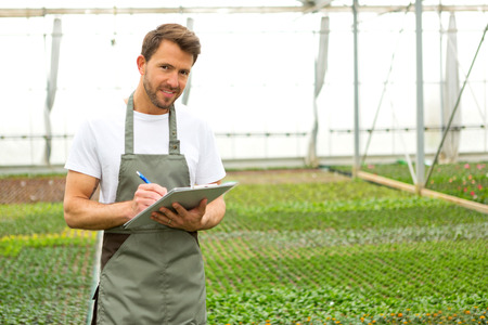 View of a Young attractive man writing notes at the plants nurseryの写真素材