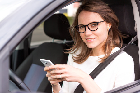 View of a Young attractive woman using mobile phone in his carの写真素材