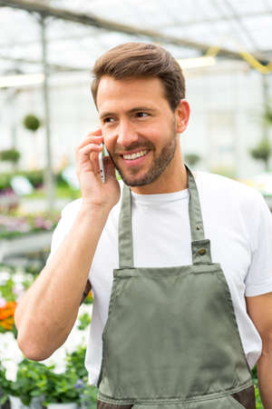 VIew of a Young attractive man working at the plants nursery using smartphoneの写真素材