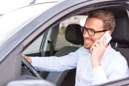 VIew of a Young attractive man using mobile phone in his carの写真素材