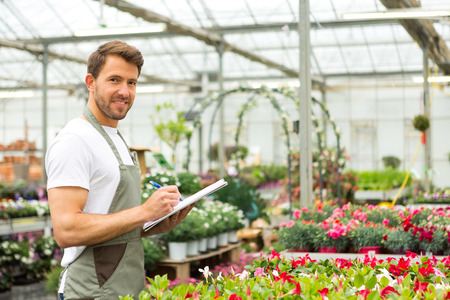 View of a Young attractive man writing notes at the plants nurseryの写真素材
