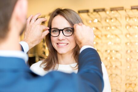 View of a Young attractive  woman testing new glasses with opticianの写真素材