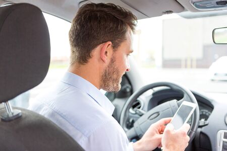 VIew of a Young attractive man using mobile phone in his carの写真素材