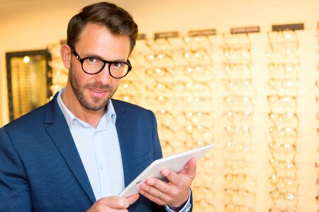 View of a Attractive optician working with tablet in his glasses shopの写真素材