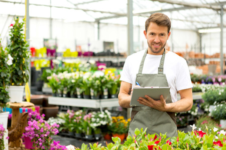 View of a Young attractive man writing notes at the plants nurseryの写真素材