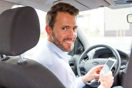 VIew of a Young attractive man using mobile phone in his carの写真素材