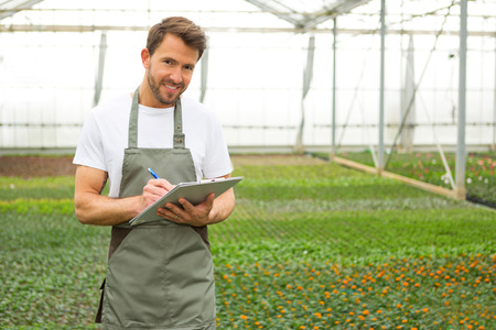 View of a Young attractive man writing notes at the plants nurseryの写真素材