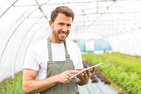 View of an attractive farmer in a greenhouse using tabletの写真素材