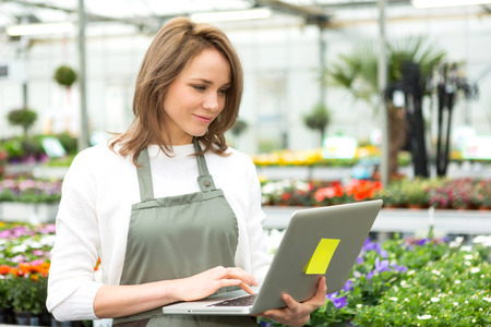 View of a Young attractive woman working at the plants nursery using laptopの写真素材