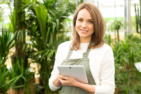 View of a Young attractive woman working at the plants nursery using tabletの写真素材
