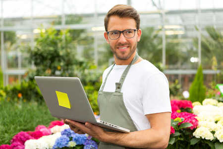 View of a Young attractive man working at the plants nursery using laptopの写真素材