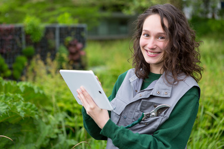 View of a Young attractive woman working in a public garden using tabletの写真素材