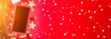 Smartphone in Christmas red background view with tree, gift and decoration