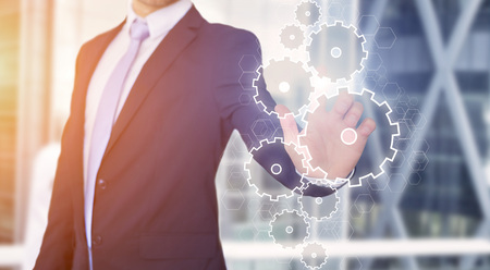 View of a Businessman touching technology interface with gear wheel settingの写真素材