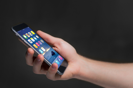 View of a Hand holding black smartphone with operating system screenの写真素材