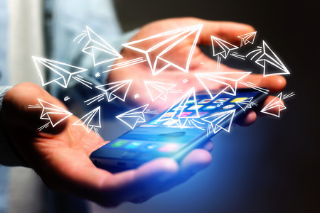 Concept view of creativity with flying paper plane over a smartphoneの写真素材