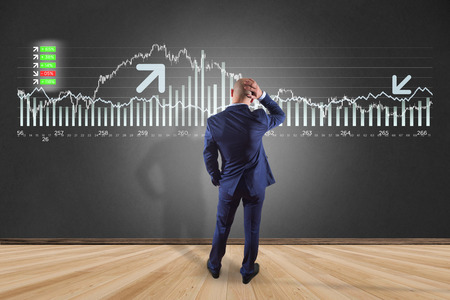 View of a Man in front of a wall thinking about a stock exchange interface - tradex conceptの写真素材
