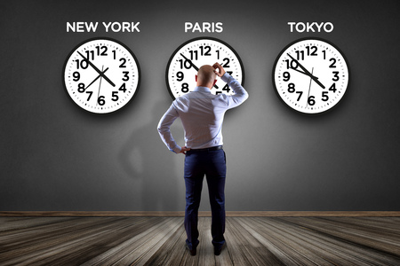 View of a Businessman in front of a wallwith clocks of different country - Jetlag conceptの写真素材
