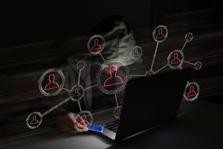 View of a Hacker man in the dark using computer to hack data and information systemの写真素材