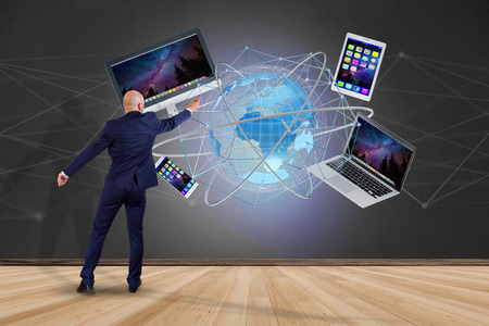 View of a Businessman in front of a wall with a Computer and devices displayed on a futuristic interface with international network  - 3d renderの写真素材