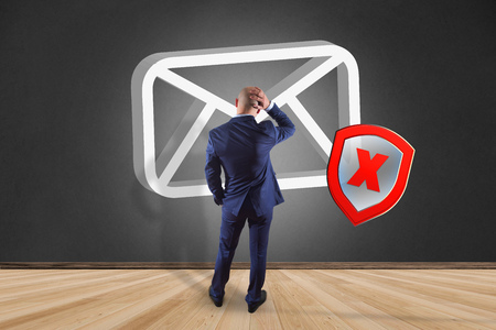 View of a Businessman in front of a wall with Spam message Email symbol displayed on a futuristic interface - Message and internet conceptの写真素材
