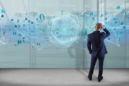 View of a Businessman in front of a wall with blockchain title with 0 and 1 data flying overの写真素材
