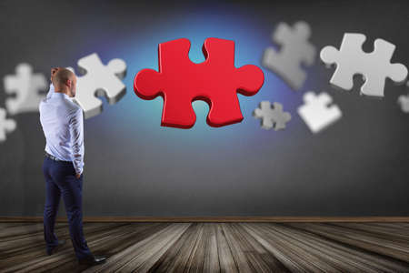 View of a Businessman in front of a wall with Puzzle pieces