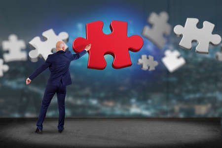 View of a Businessman in front of a wall with Puzzle piecesの写真素材