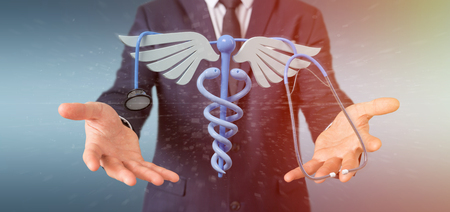 View of a Businessman holding a 3d redering medical cadaceus and stethoscopeの写真素材