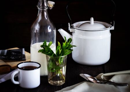 A teapot, cup and a bottle of milk on a wooden tableの写真素材