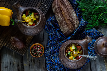 Ceramic pots with meat and vegetables,bread,greens and pepper on wooden background. Style rustic. Overhead.Selective focus.の写真素材
