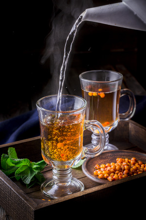 Hot tea flowing in glass cup with berries. Dark background.Selective focus.の写真素材