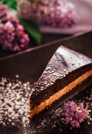 Slice of cake on the plate decorated by flowers. Selective focus.