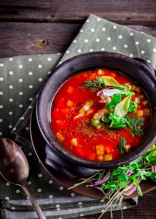 Tomato cream soup in ceramic bowl and herbs on wooden table. Selective focus.の写真素材