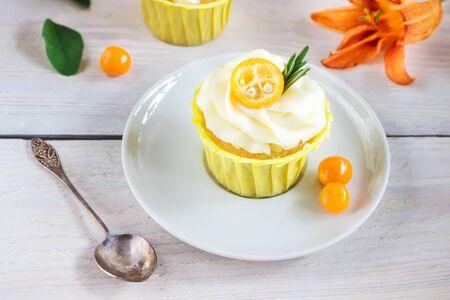 Cupcakes with cream cheese and orange flower on white wooden table. Selective focus.の写真素材