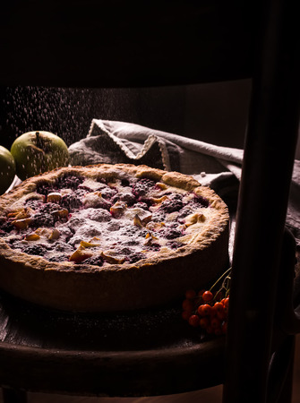 Homemade pie with apples and blackberry and pouring icing on dark background. Style rustic.の写真素材