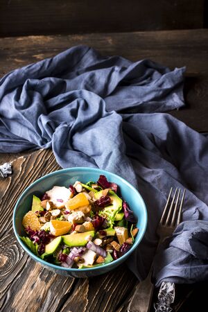 Orange, avocado, blue cheese, chicken and onions salad in a blue bowl on a wooden background. Wooden background. Selective focusの写真素材